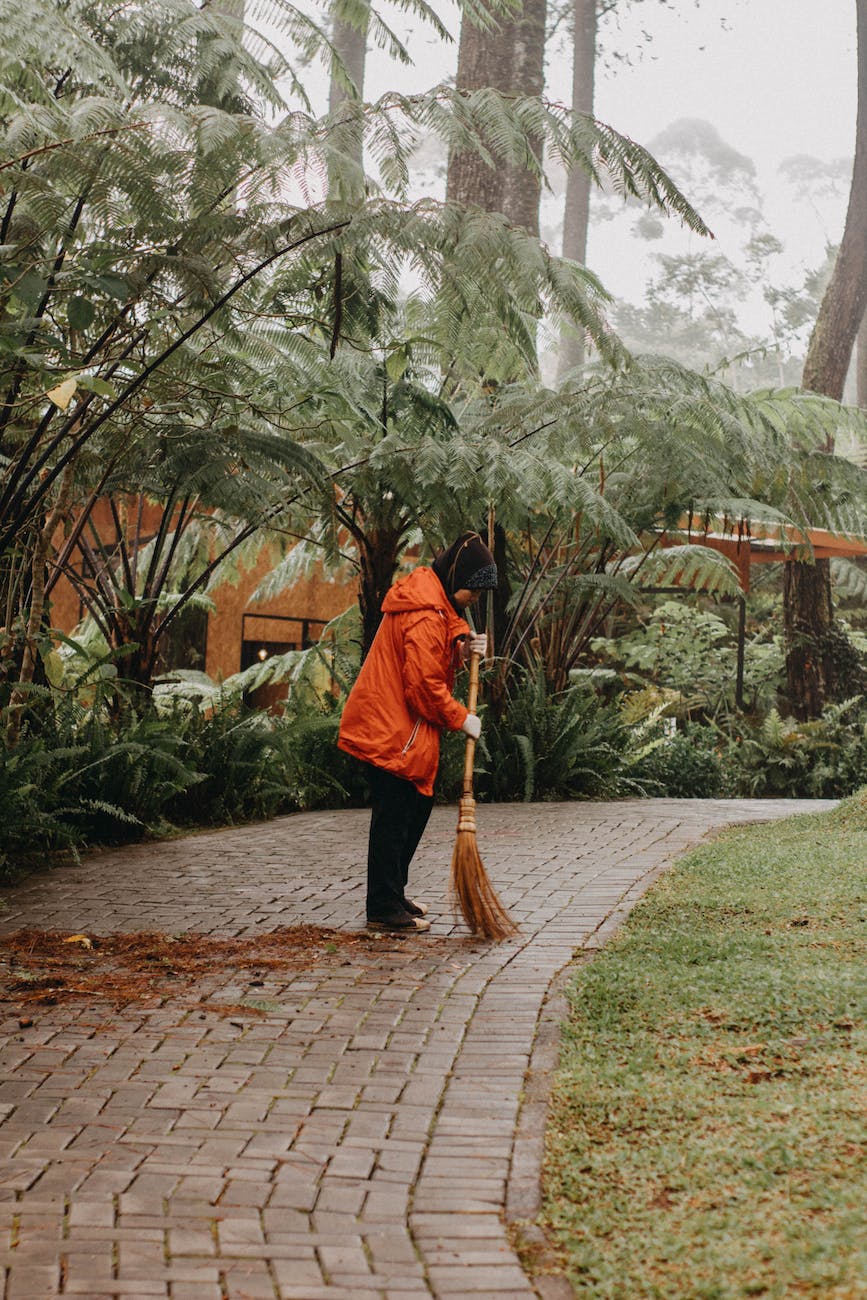 a person in orange jacket sweeping on the street