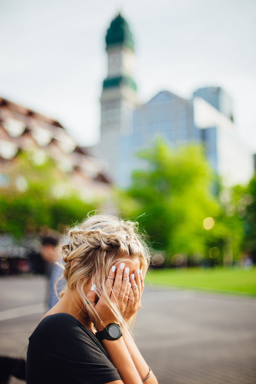 woman in black shirt covering her face