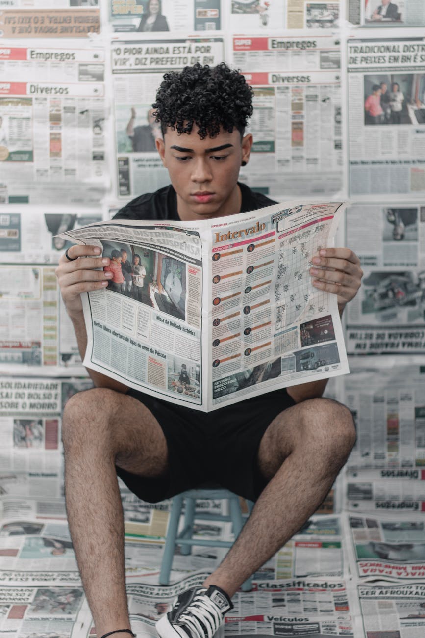 concentrated ethnic man reading newspaper at home